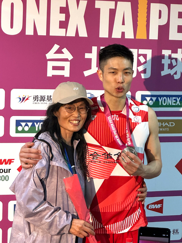 「台灣一哥」周天成（右）11日在台北羽球公開賽男單決賽拿下銀牌，趁著母親節獻上康乃馨和銀牌給媽媽劉翠蓮（左），感謝她一路支持。（圖：中央社）