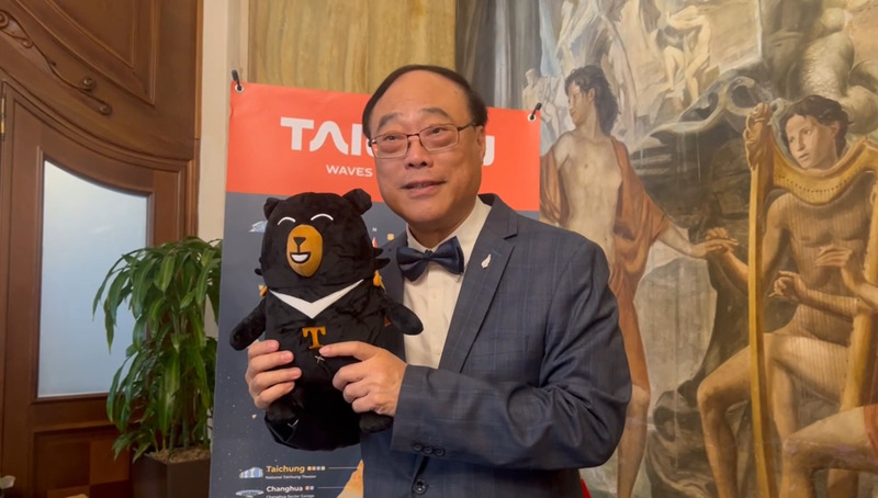 交通部觀光署到羅馬推廣台灣旅遊，觀光署長周永暉現場示範伴手禮台灣黑熊頸枕如何使用，頸枕造型可愛又實用，受到許多參加者喜愛。 (圖：中央社)