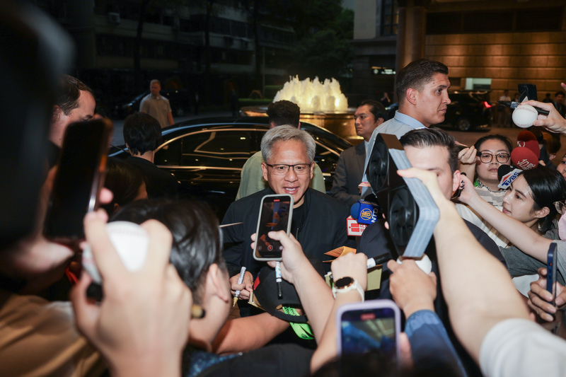 輝達（NVIDIA）執行長黃仁勳（中）19日結束下午行程，為現場等候許久的粉絲簽名。 (圖：中央社)