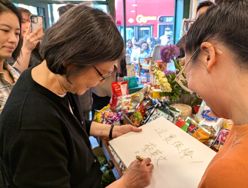 前總統蔡英文（左）18日造訪台灣人在倫敦開設的亞洲超市，為店家簽名留念。 (圖：中央社)