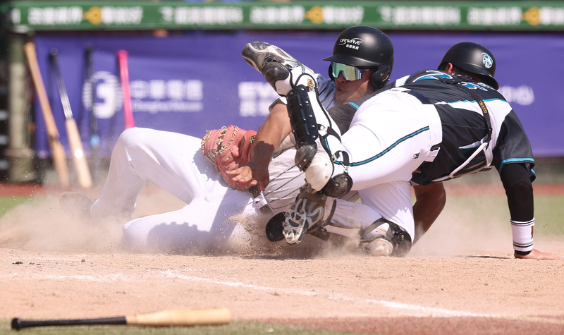 世壯運棒球男子35+組23日進行第2天的賽事，山羊兄弟隊與Energy隊在天母棒球場出賽，3局下Energy隊進攻時，野手鄧志偉（左）從三壘衝回本壘，與山羊兄弟隊捕手吳明訓（右）在本壘發生攻防戰。 (圖：中央社)