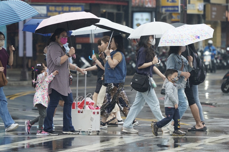 氣象署25日表示，29日鋒面影響，全台有雨，可能有局部豪雨；端午連假水氣漸減，預估各地高溫可回升至30度以上。圖為25日台北西門町，民眾撐傘過馬路。(圖：中央社)